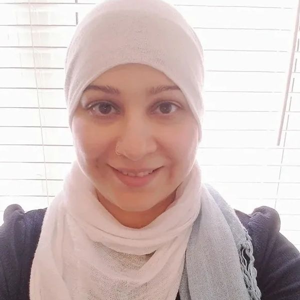 student therapist khulood khan smiling against a shuttered window background