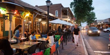 People dining outdoors at a lively street restaurant during early evening.