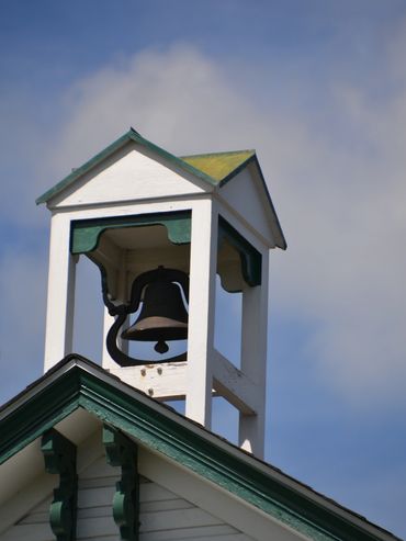 A classic school bell tower atop a white building against a blue sky.