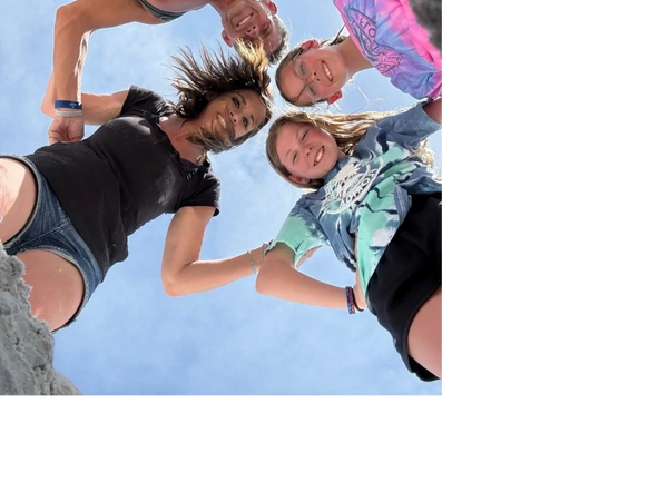 Four people smiling and looking down into a hole on a sunny day.
