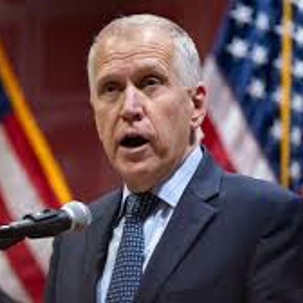 Man speaking at a podium with American flags in the background.