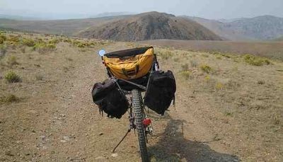Bike loaded with bags on a trail in a mountainous area.