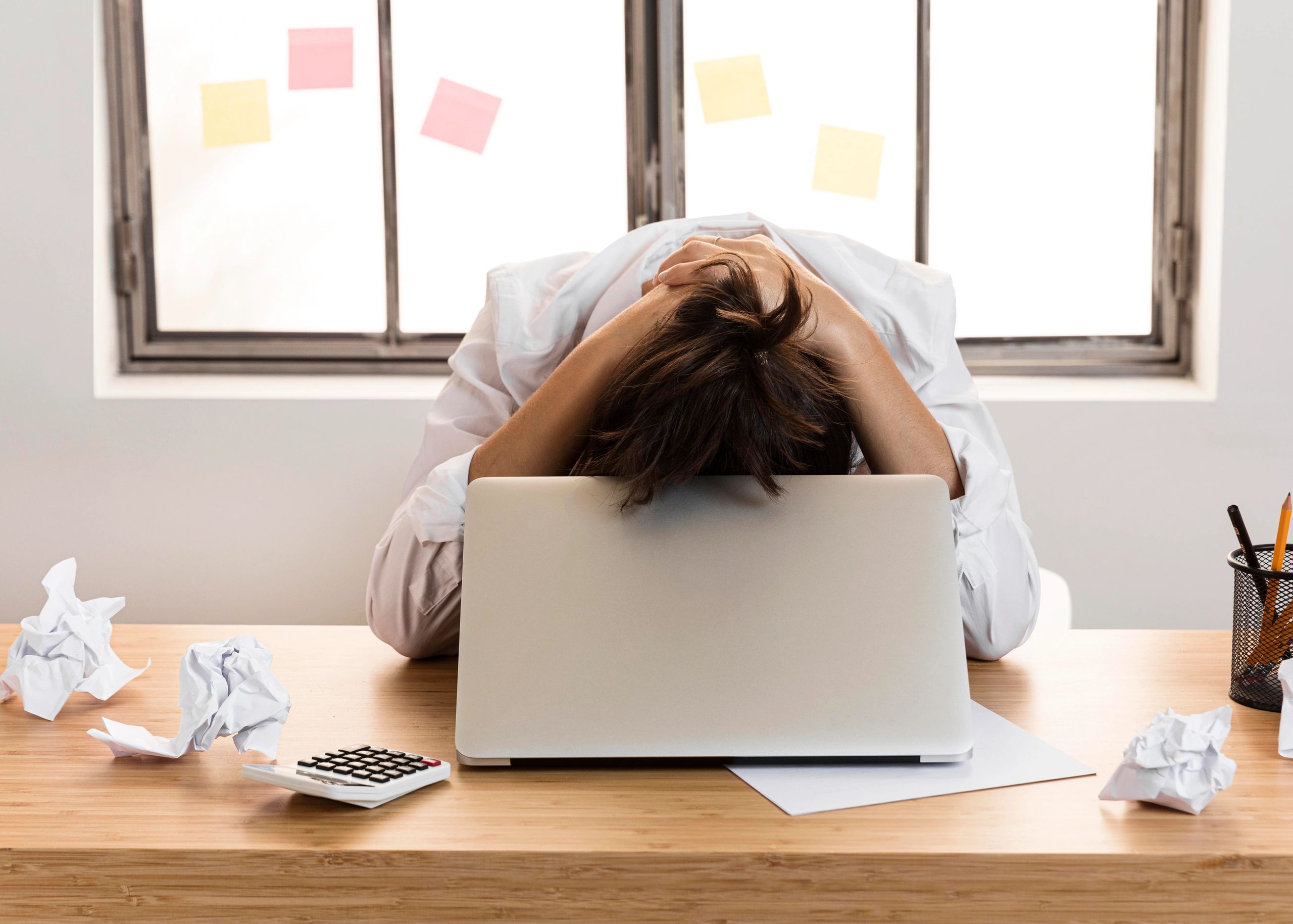 Woman lowering her head in frustration over her computer