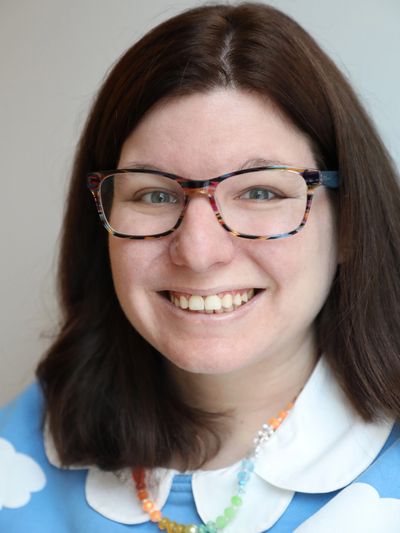 Smiling woman with glasses and a colorful necklace.