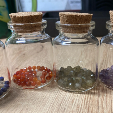 pequeños frascos de vidrio con muestras de piedras naturales de diferentes colores