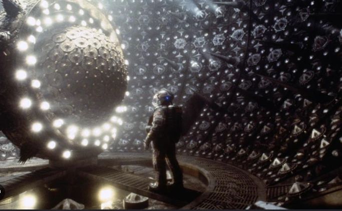 Astronaut in a futuristic, illuminated chamber with a glowing spherical object.