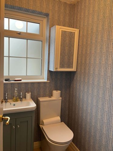 Water closet wall painted and wall paper installed including on the cabinet