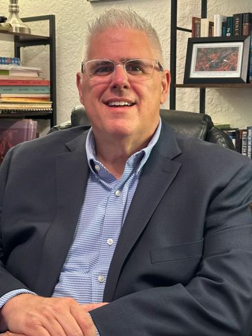 A smiling man in a suit sitting in an office.