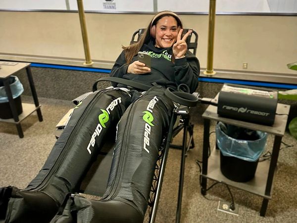 Woman smiling while using a full-body compression recovery device.