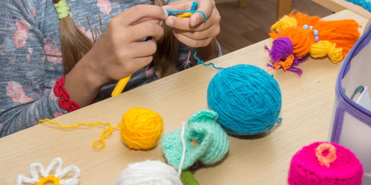 Child learning embroidery stitches with needle and colorful thread at UMAI Foundation.