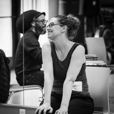 Woman smiling and leaning forward in a casual setting.