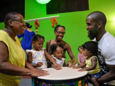 Adults and children smiling around a drum.