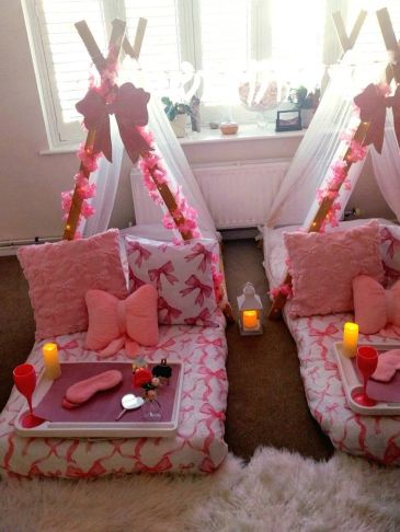 Cozy pink teepee setup with pillows and snacks for two.