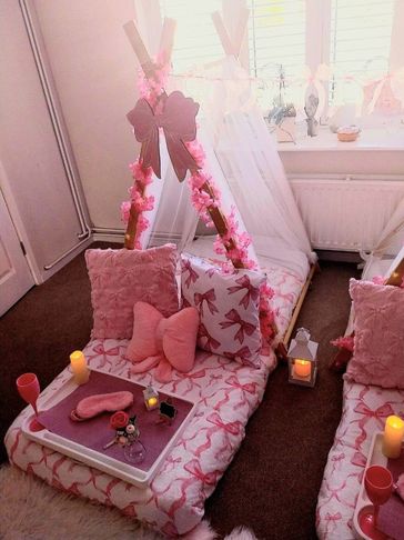 Cozy pink indoor tent setup with pillows and candles.