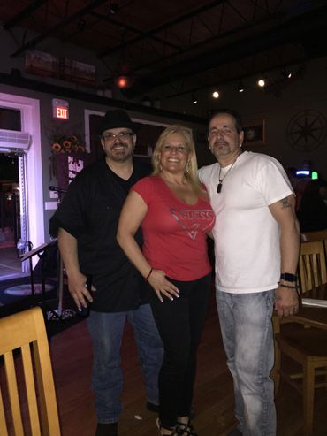 Three friends posing together in a dimly lit bar.