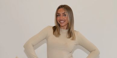 Smiling woman in a beige top posing confidently.