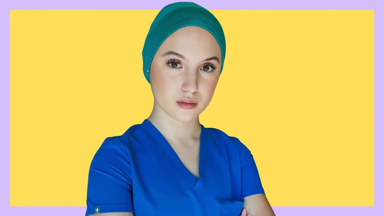 Young woman in blue scrubs and teal cap.