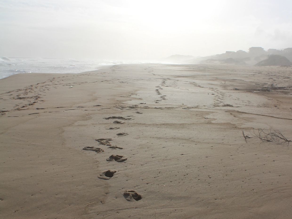 Single set off footsteps on sand represent your walk through life alone. God is with you.