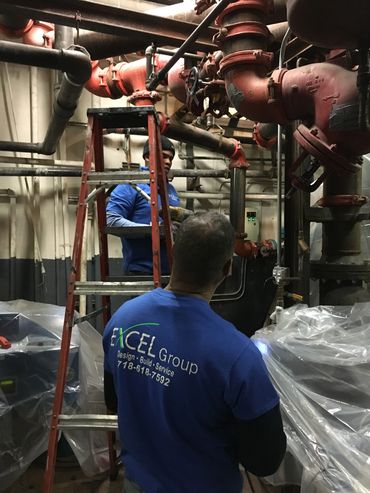 Two workers fixing pipes in an industrial setting.