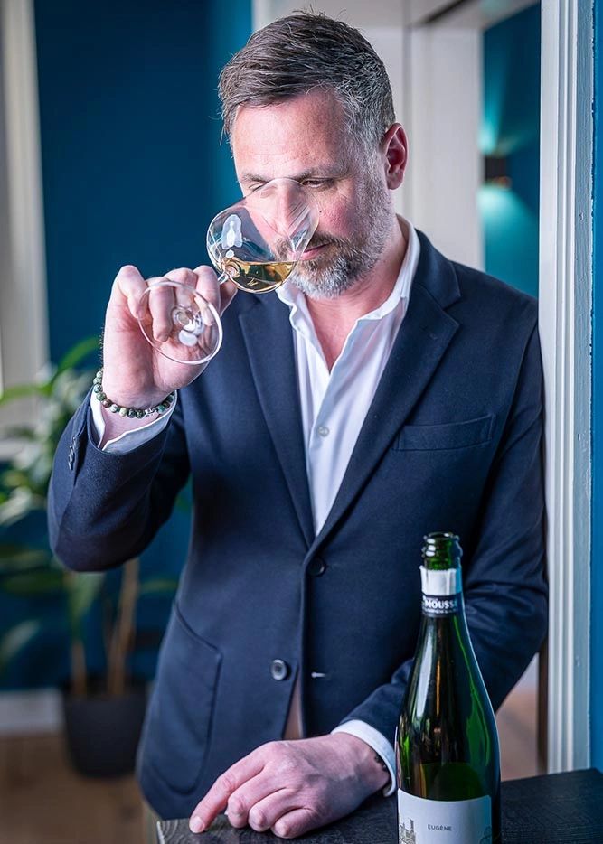 Man in suit smelling white wine from a glass.