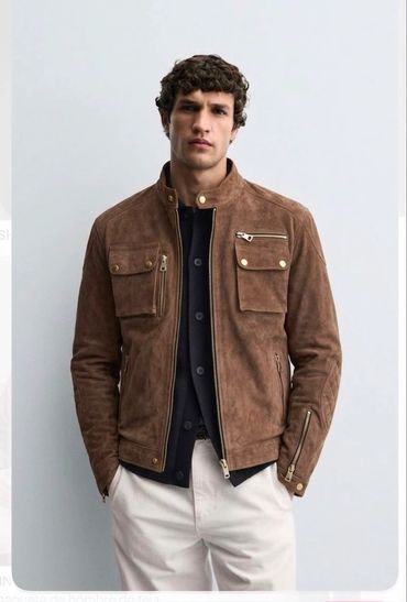 Hombre con chaqueta marrón de gamuza y pantalones claros.