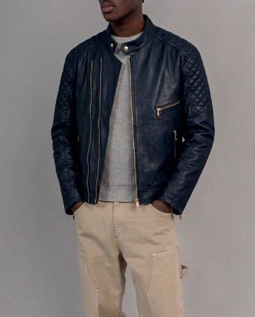Hombre con chaqueta de cuero y pantalones beige.