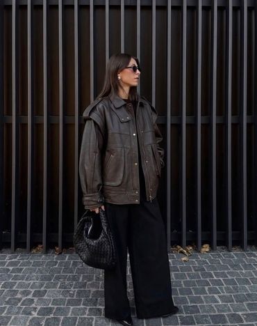 Mujer con chaqueta de cuero y pantalones anchos negros.