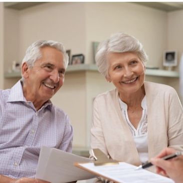 Elderly couple smiling during a consultation with a professional.