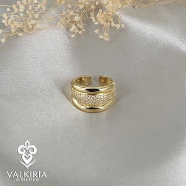 Elegant gold ring with embedded crystals on a silky silver fabric.