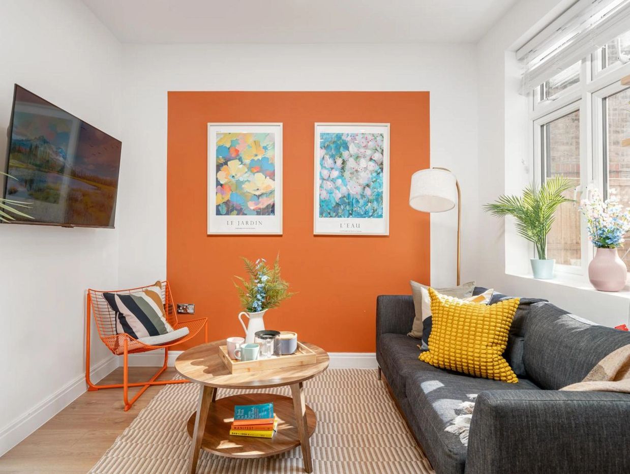 Cozy living room with orange accent wall and modern decor.