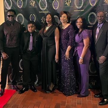 Group of people dressed elegantly at a formal event with a Grand Prairie NAACP backdrop.