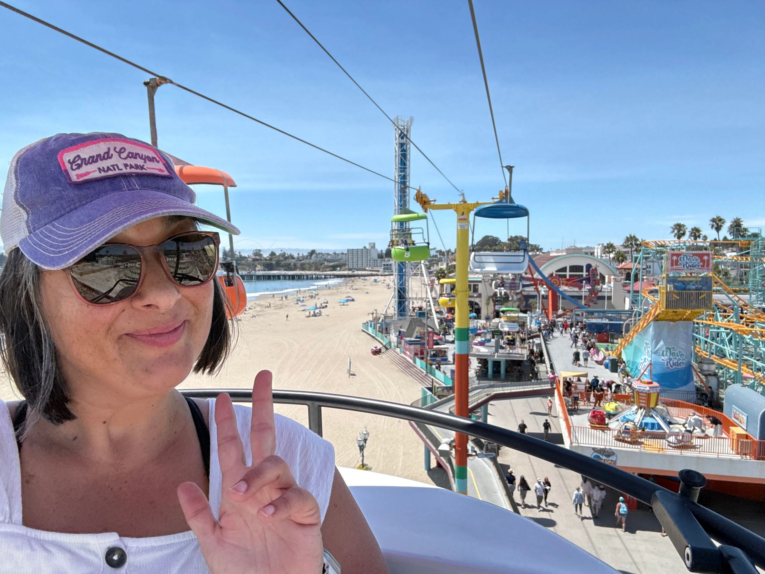 Woman wearing Grand Canyon hat on a cable car at a beach amusement park.