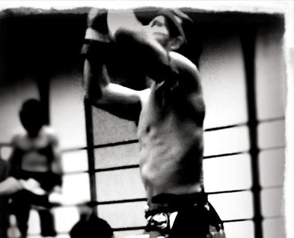 Black and white photo of a boxer in a ring preparing to strike.