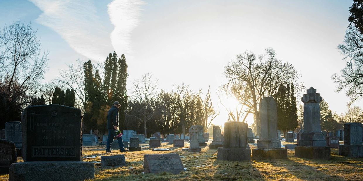 A man is walking to a gravesite.