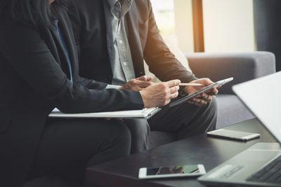 Two business professionals reviewing documents and using a tablet during a meeting.