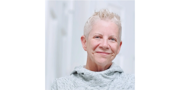 Smiling older woman with short white hair and cozy sweater.
