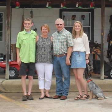 Family standing together outside a building with a dog.