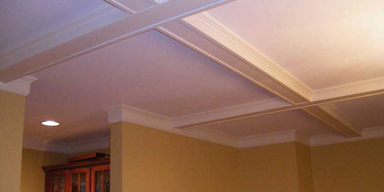 White coffered ceiling with recessed lighting in a beige room.