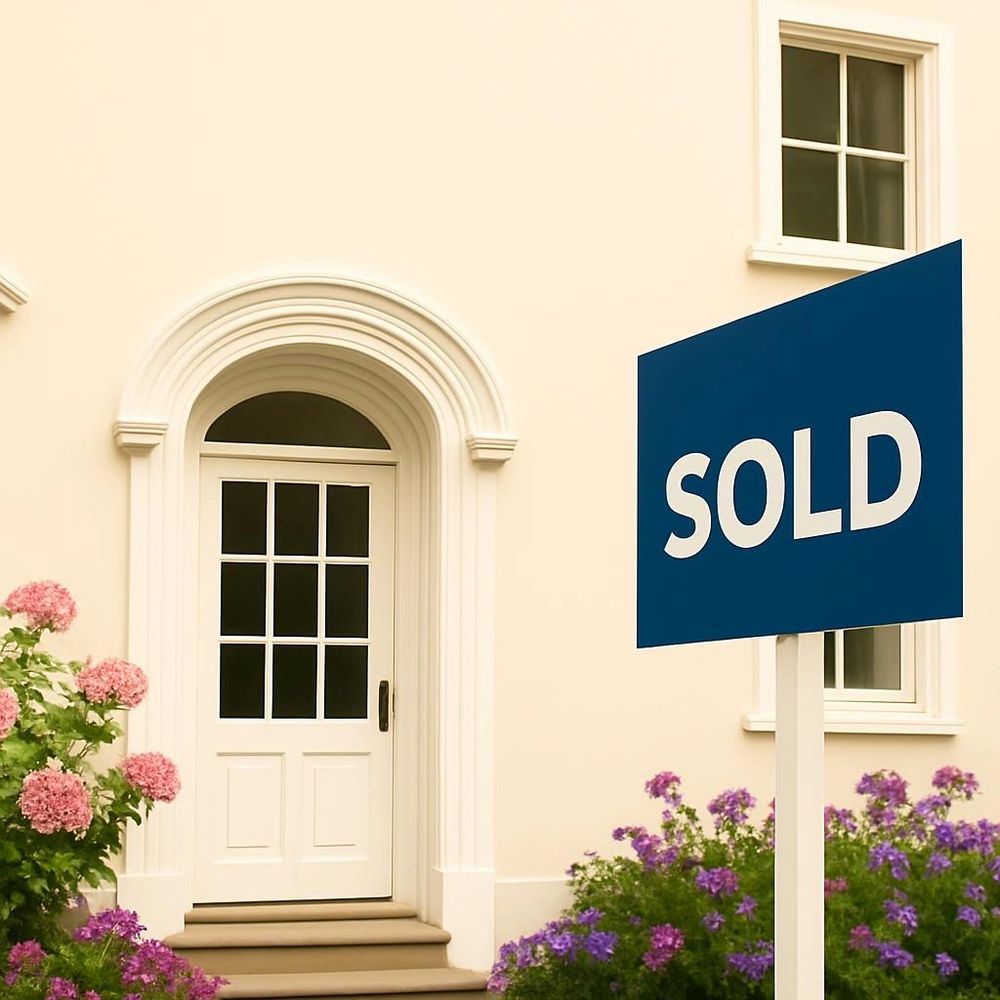 A charming house entrance with a sold sign and colorful flowers.
