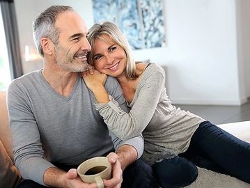 Smiling couple relaxing at home with coffee.