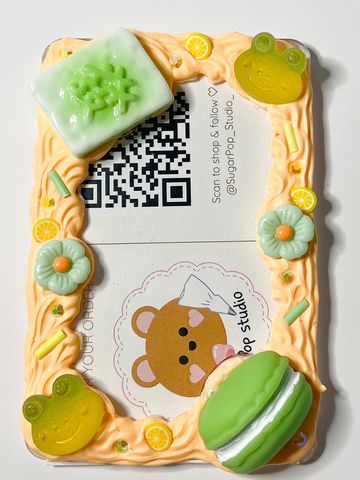 Decorative phone frame with cute frog, flower, and macaron motifs in pastel colors.