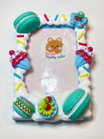 A colorful dessert-themed photo frame with cupcakes, macarons, and sprinkles.