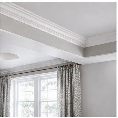 Elegant living room ceiling with crown molding and patterned curtains.