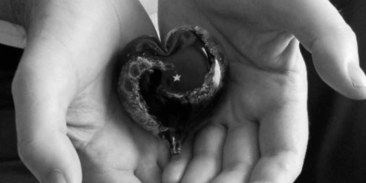 Hands holding a heart-shaped object with a star.