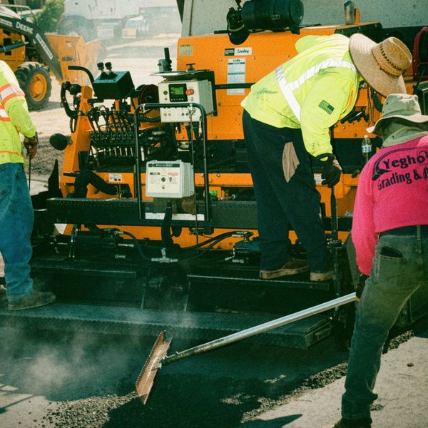 Construction workers paving a road with machinery.