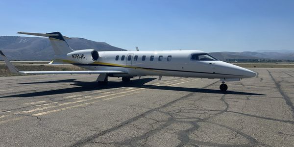 Private jet on runway under clear sky.