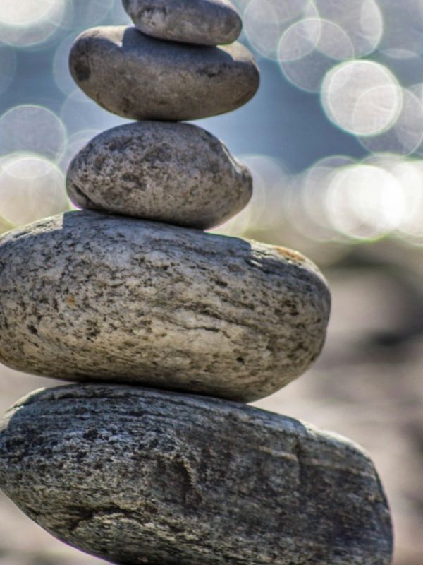 Stack of five balanced stones with a blurred, sparkling background.
