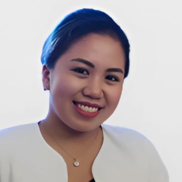 A smiling woman with neat hair and a white top against a plain background.