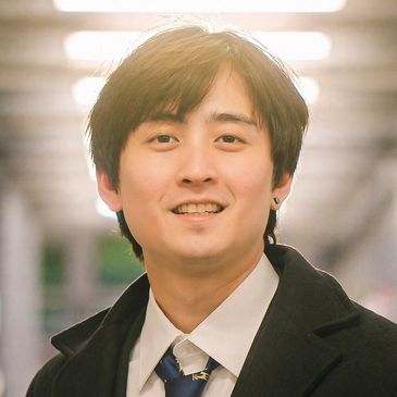 Young man smiling in a softly lit indoor setting.