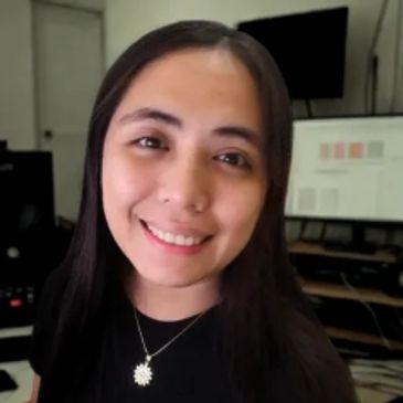 A smiling woman with long dark hair in an office setting.